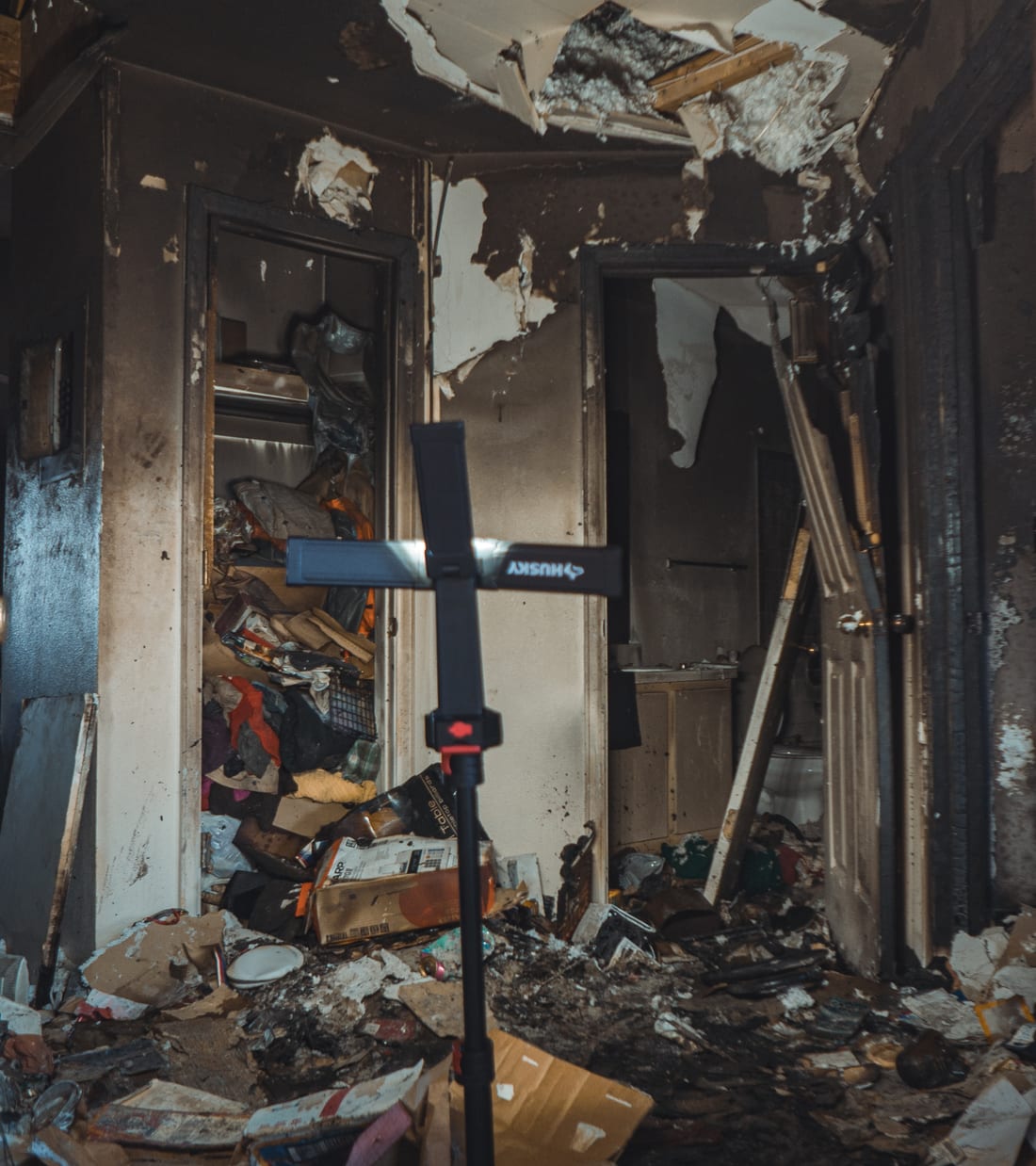 Fire-damaged interior stripped back, with a work light standing in the debris